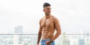 Portrait of young handsome muscular Persian man shirtless and looking macho against view of the city