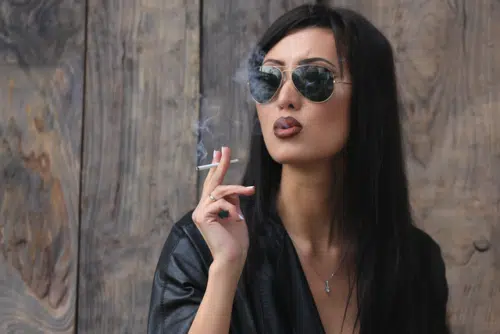 Girl In A Leather Jacket And Sunglasses Smoking A Cigarette 500x334